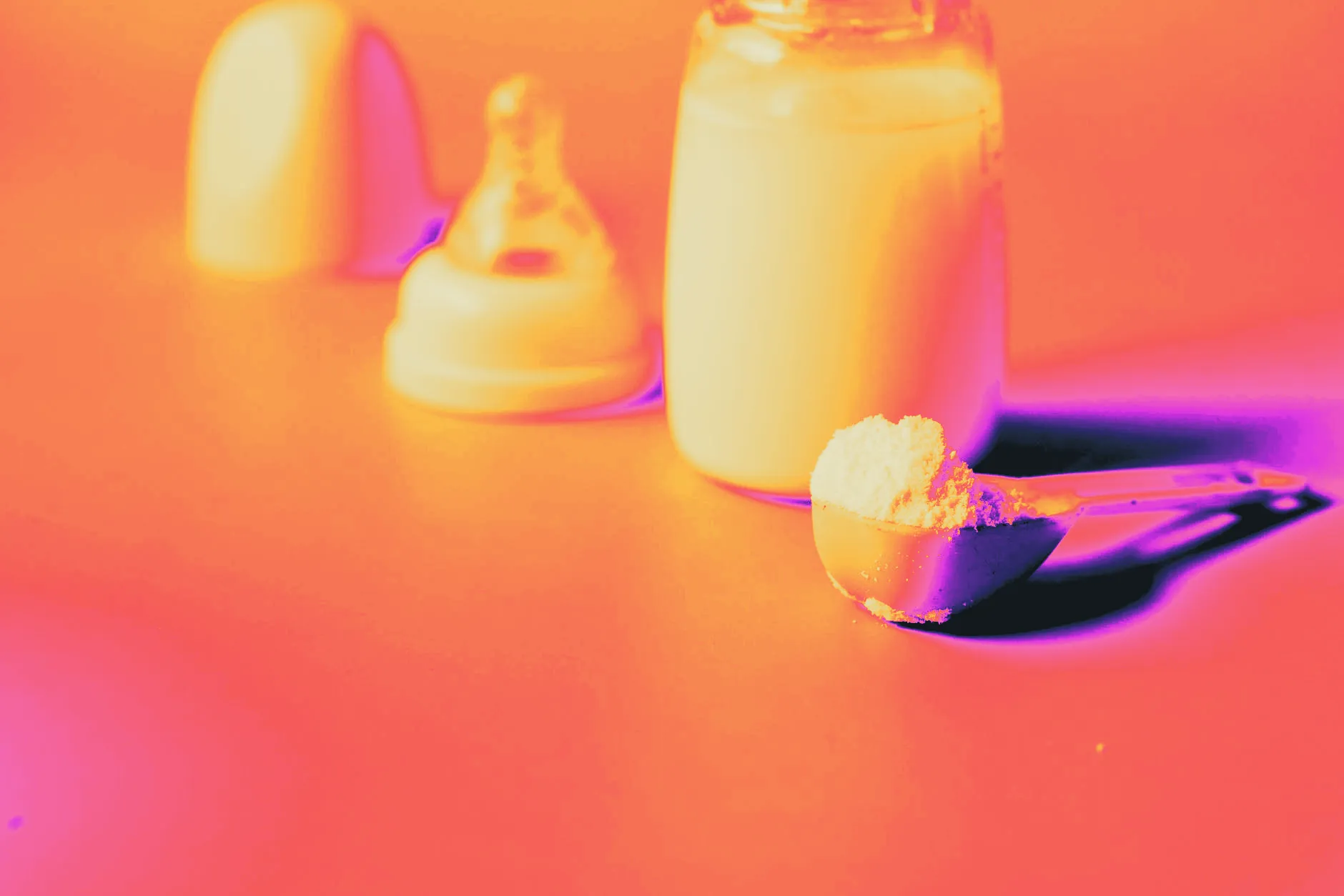 Powder formula being scooped while preparing a baby bottle