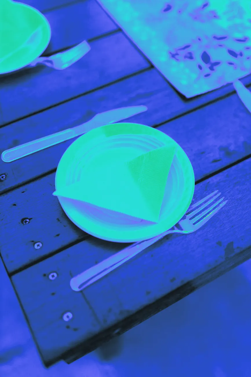 Paper plates and plastic forks set out on an outdoor picnic table