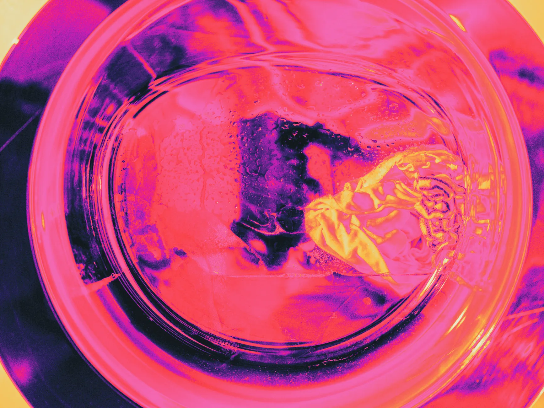 A thin detergent sheet beginning to dissolve in washing machine water