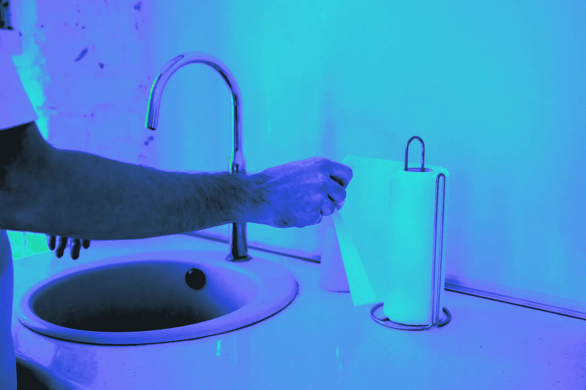 A paper towel being torn from the roll in a kitchen