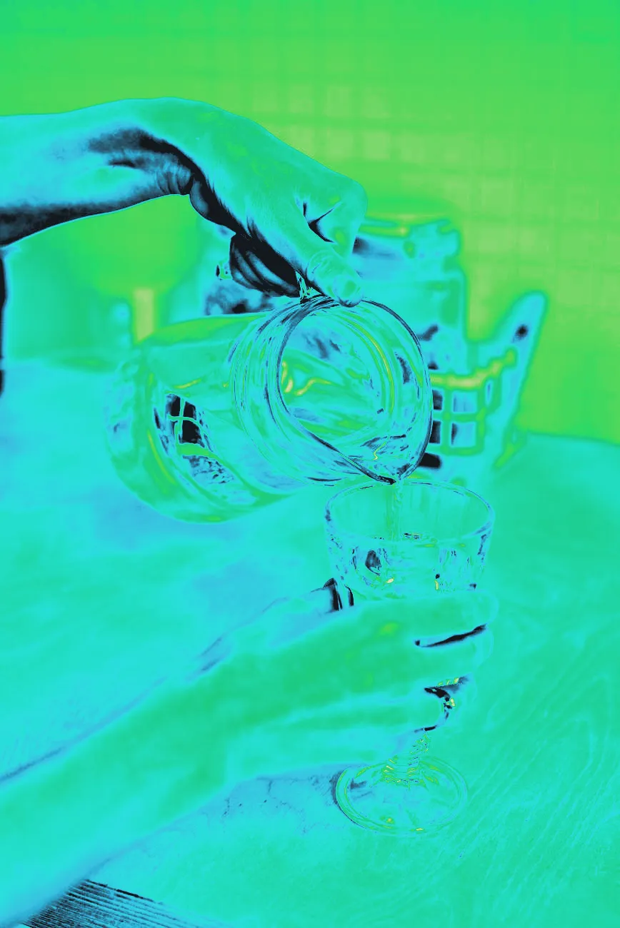 A pitcher pouring water into a glass on a kitchen counter